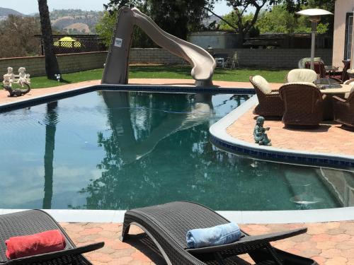 a swimming pool with two chairs and a water slide at paradise luxury experience in Woodland Hills