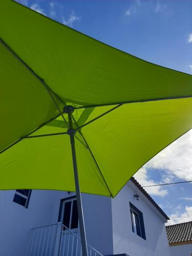 a green umbrella in front of a building at Norverde - Açores in Nordestinho