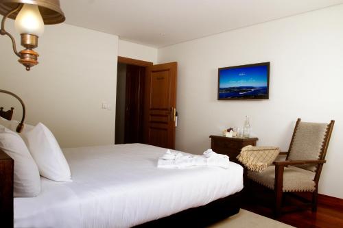 a hotel room with a white bed and a chair at Rinoterra Minho in Caminha