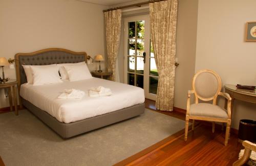 a bedroom with a bed and a chair and a window at Rinoterra Minho in Caminha