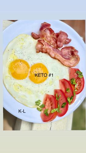 a plate of food with eggs bacon and tomatoes at Hotel Beachfront Vista Hermosa in Jacó