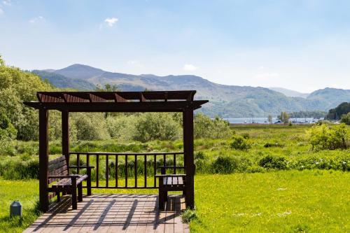 two benches sitting under a gazebo in a field at The Derwentwater Hotel in Keswick
