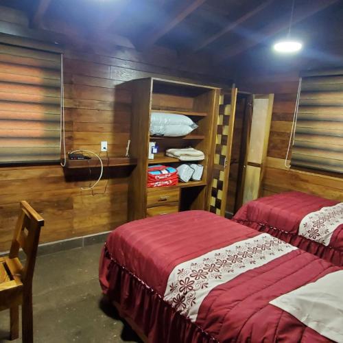 two beds in a room with wooden walls at Cabañas Corazón in Troncones