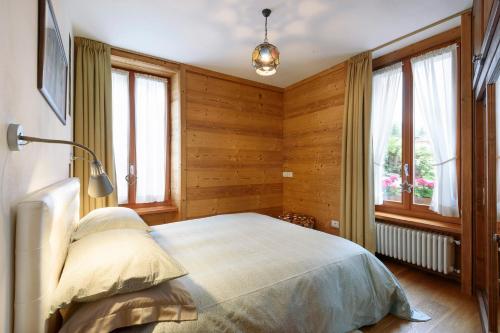 una camera da letto con un letto, pareti e finestre in legno di Appartamento Casa Weisstor con patio, giardino e orti vista Monte Rosa a Macugnaga