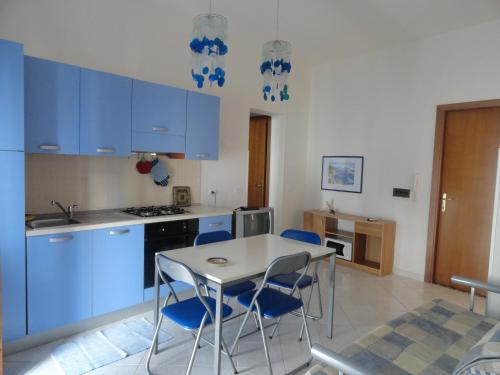 cocina con armarios azules, mesa y sillas en Il Cortile Di Eolo, en Marettimo
