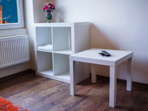 a white table next to a book shelf with flowers at Boutique Hostel in Łódź