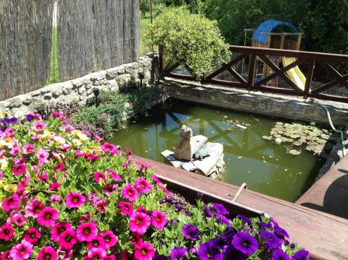 a garden with flowers and a pond with a bridge at Ubytovanie Anka Sučanská in Čachtice