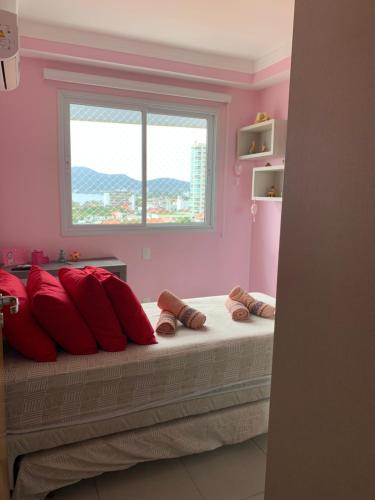 1 dormitorio con paredes rosas y 1 cama con almohadas rojas en Apartamento Família Santos, en Penha