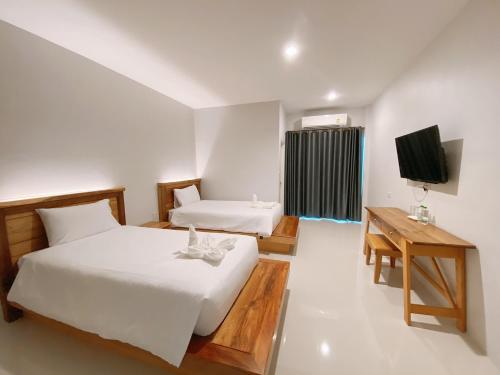 a hotel room with two beds and a television at Greenish Ranong Hotel in Ranong