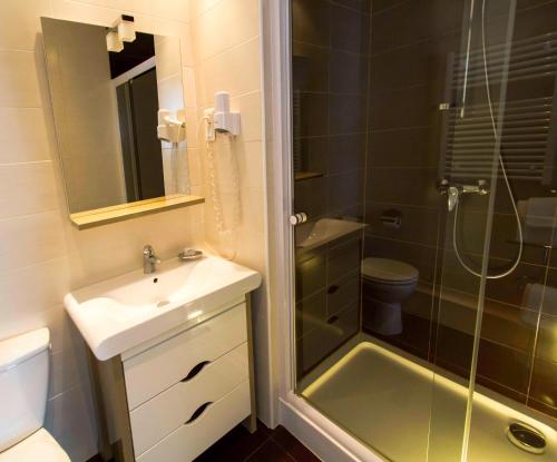 a bathroom with a sink and a shower and a toilet at Hôtel Le Divona in Divonne-les-Bains