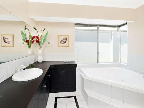 y baño con bañera blanca, lavamanos y bañera. en Busselton Beach House with WiFi, en Busselton