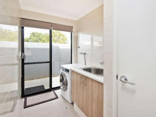 a bathroom with a sink and a washing machine at Ocean Walk Abbey in Vasse