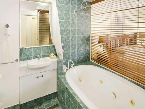 a bathroom with a tub and a sink at Sixteen at Cape View Escapes in Busselton