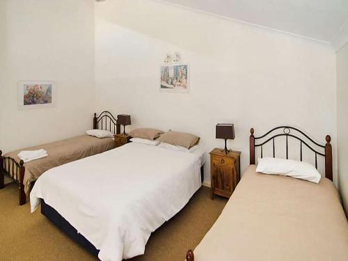 two beds in a room with white walls at Sixteen at Cape View Escapes in Busselton