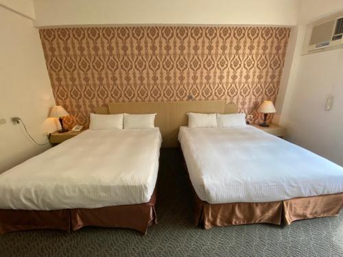 a hotel room with two beds and a wall at Dreamer Hotel in Budai