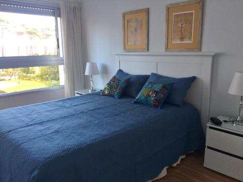 een slaapkamer met een blauw bed en een raam bij Playa Mansa Parada 8 in Punta del Este