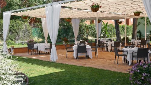 a patio with tables and chairs under a pavilion at Hipotels Sherry Park in Jerez de la Frontera