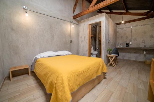 1 dormitorio con 1 cama amarilla y cocina en Ixmukané Hotel & Spa en San Cristóbal de Las Casas