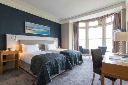 a hotel room with two beds and a desk at The St Ives Bay Hotel in St Ives