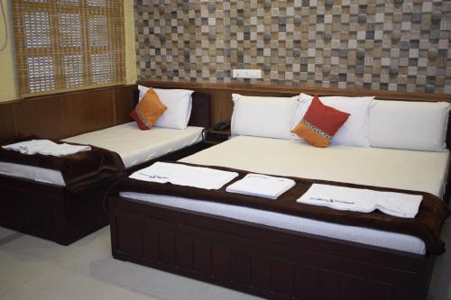 two beds sitting in a room with at Arudhra Residency in Chidambaram