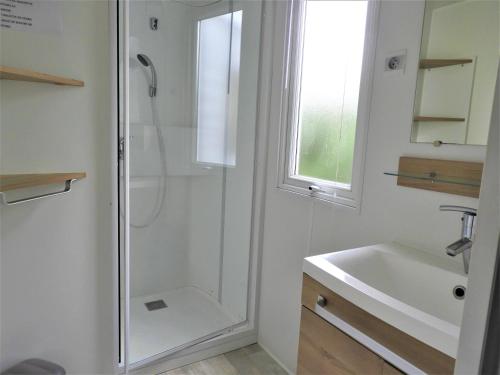 une salle de bain blanche avec une douche et un lavabo dans l'établissement Mobil home 3 chambres Saint-Jean-de-Monts, à Saint-Jean-de-Monts