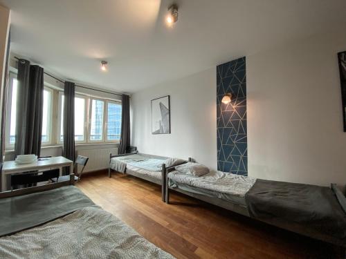Un dormitorio con dos camas y un escritorio y ventanas. en Pokoje PANORAMA CITY VIEW- Centrum, en Varsovia