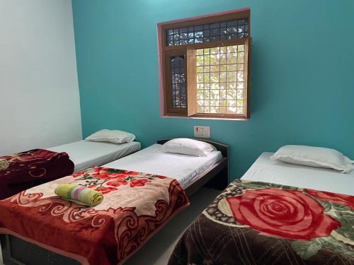 two beds in a room with a window at Senamura Yoga Ashram Guesthouse in Bodh Gaya