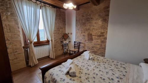 1 dormitorio con cama, ventana y silla en La scuola del castello località San Giovanni Spello, en San Giovanni