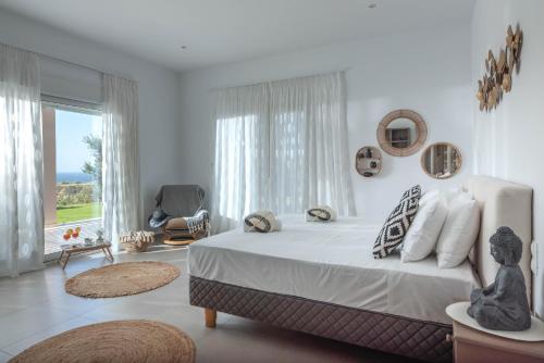 a white bedroom with a large bed and a chair at SAMIRAM in Koutsounari