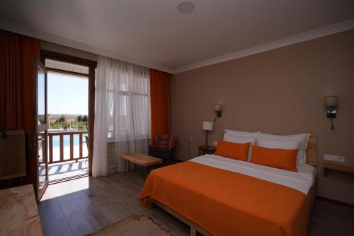 1 dormitorio con cama de color naranja y balcón en Vinum Bağ Oteli & Spa Tennis Courts By Edrine Vine, en Edirne