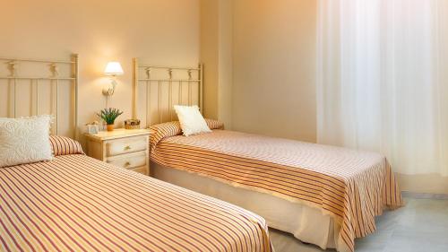1 dormitorio con 2 camas y mesa con lámpara en Life Apartments Costa Ballena, en Costa Ballena