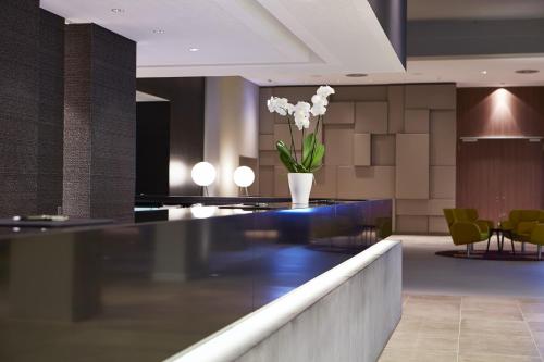a lobby with a counter with a vase of flowers at Steigenberger Hotel Am Kanzleramt in Berlin