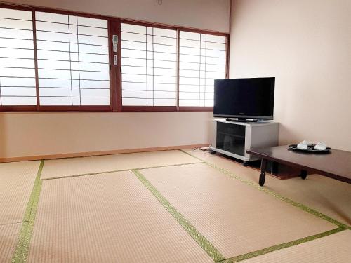 a living room with a flat screen tv and a table at Business Ryokan Wakakusa in Tsu