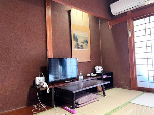 a living room with a television on a table at Business Ryokan Wakakusa in Tsu
