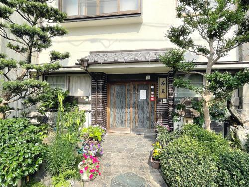 a front door of a house with flowers and plants at Business Ryokan Wakakusa in Tsu