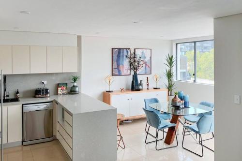a kitchen with a table and blue chairs in it at Crows Nest - Executive Penthouse - 3 Bedroom- 5km to City in Sydney