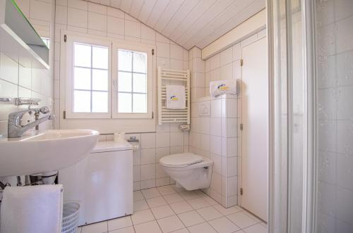 a white bathroom with a sink and a toilet at Chalet Soldanella by Arosa Holiday in Arosa
