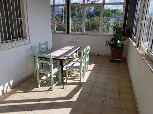 una mesa y sillas en una habitación con ventanas en Stylish Apt TERINA - Le Lincelle, Lamezia - bright, spacious, elegant and with terrace en SantʼEufemia Lamezia