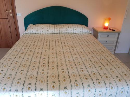 a large bed with a green headboard and a candle on a table at Stylish Apt TERINA - Le Lincelle, Lamezia - bright, spacious, elegant and with terrace in SantʼEufemia Lamezia