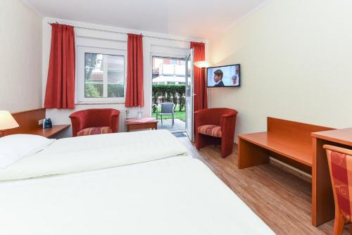 a hotel room with a bed and a desk and chairs at Hotel Garni Benser Watt in Bensersiel