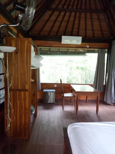 a room with a bed and a table and a window at Pier26 Bali Homestay in Nusa Dua