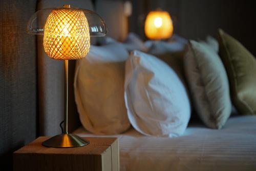 a lamp on a table next to a bed with pillows at Les Terrasses des Falizes B&B in Rochefort