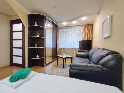 a room with a bed and a leather couch at Apartament on Gorkogo 26 in Bobruisk