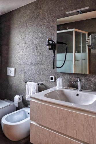 a bathroom with a sink and a mirror and a toilet at Hotel Panorama Wellness & Resort in Malosco