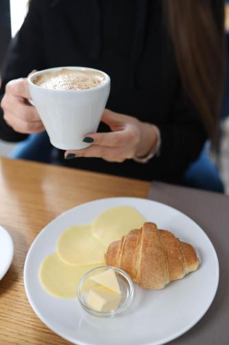a woman holding a cup of coffee and a plate of food at SPA-Hotel Dodo in Zhytomyr