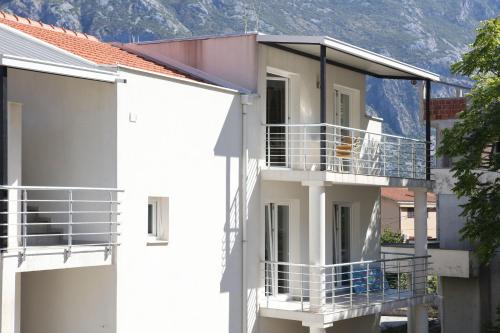 ein weißes Apartmenthaus mit einem Hund auf dem Balkon in der Unterkunft Luxury Seefracht Flat Perzagno 1 in Prčanj