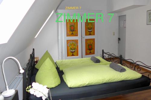 a bed with green sheets and pillows in a room at Pension Jeske Heidelberg in Heidelberg