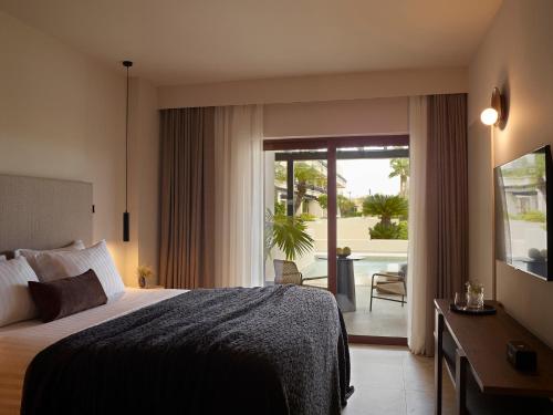 a hotel room with a bed and a sliding glass door at Asterion Suites & Spa - Designed for Adults in Gerani Chanion