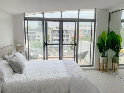 a bedroom with a white bed and a large window at Crows Nest - Executive Penthouse - 3 Bedroom- 5km to City in Sydney