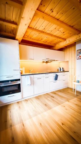 a kitchen with white cabinets and a wooden floor at Bergquelle 1.OG Ost in Bettmeralp